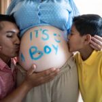 Father and son kissing pregnant mother and doing gender reveal at the living room at home