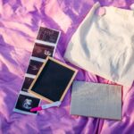 Pregnancy Testing Kit, Ultrasound Pictures, Notebook, Small Chalkboard And A Tote Bag On A Purple Blanket