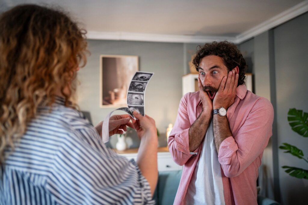 Woman showing ultrasound images to surprised man